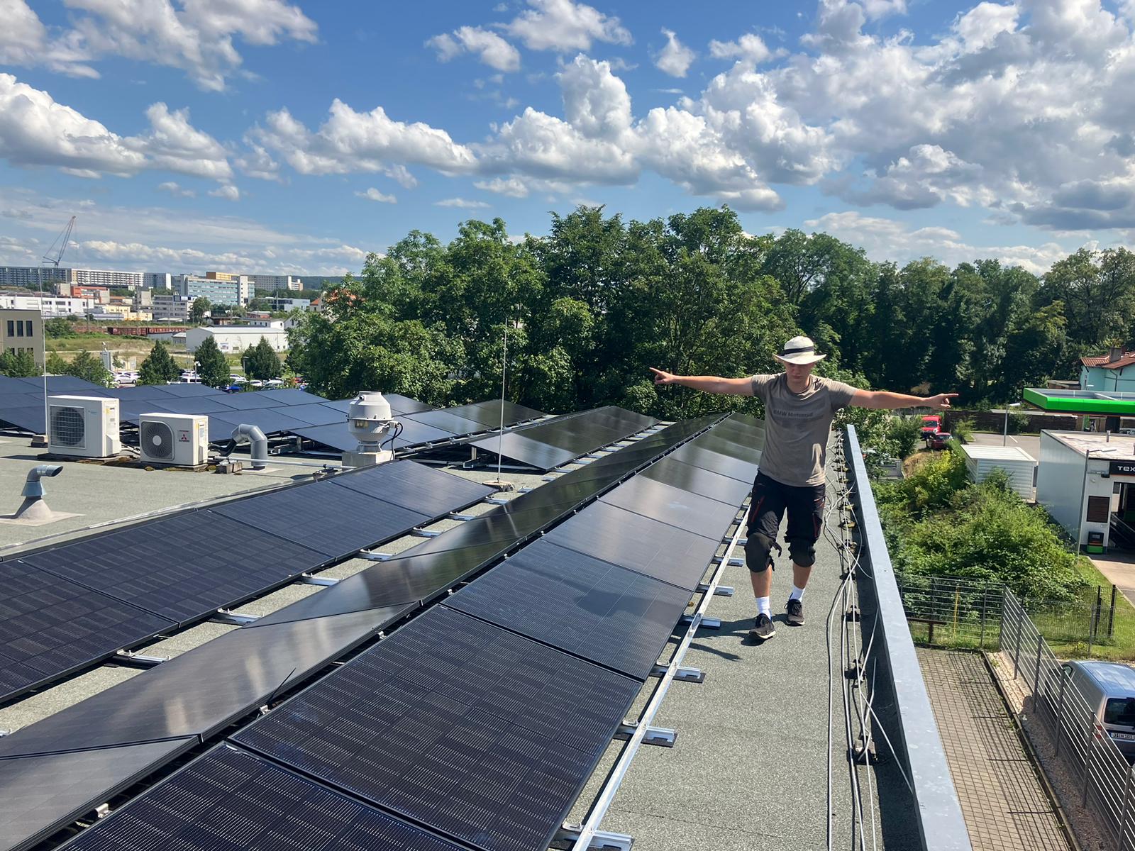 Mitarbeiter auf Flachdach neben installierter Photovoltaikanlage